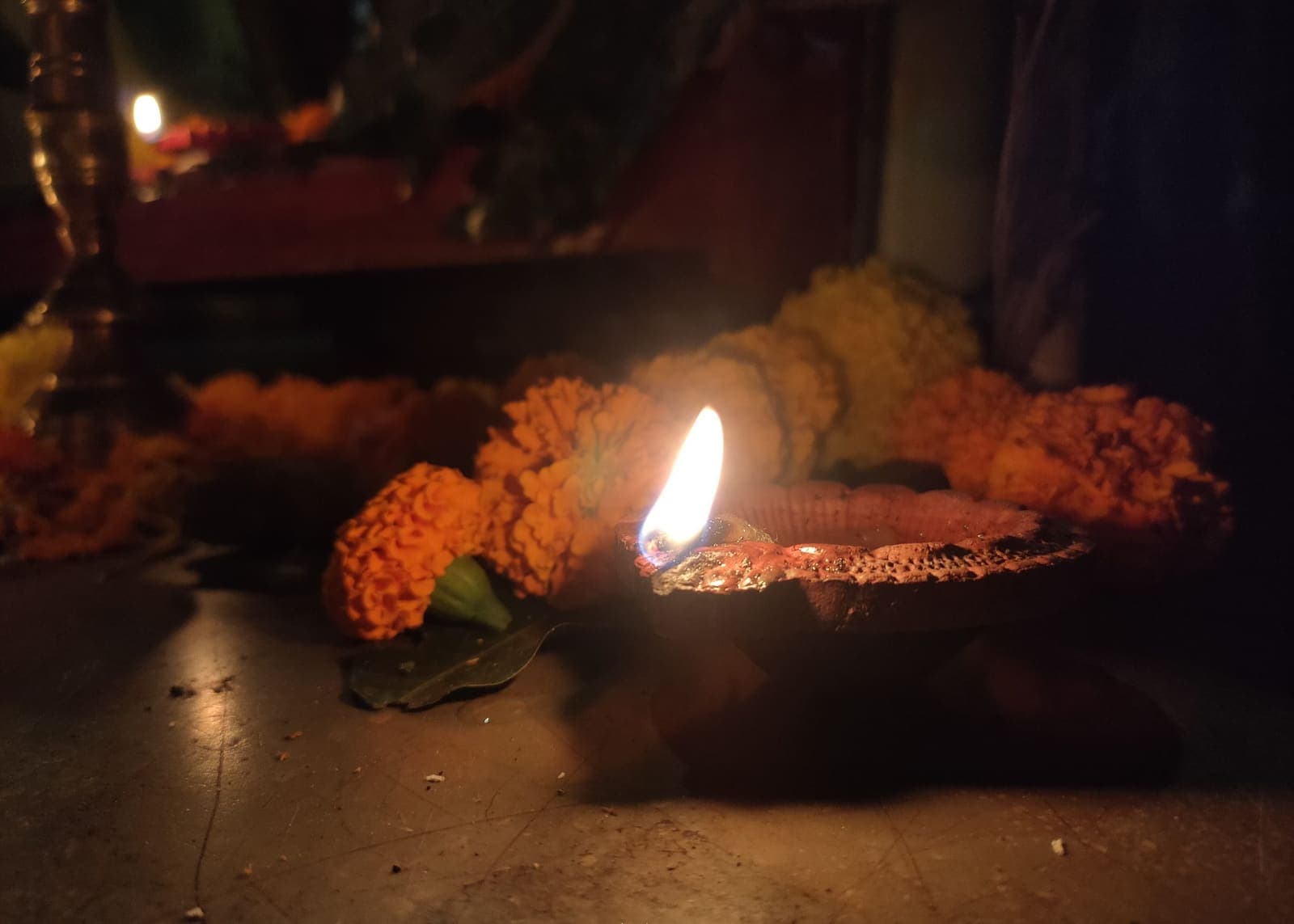 A lit diya among marigold flowers