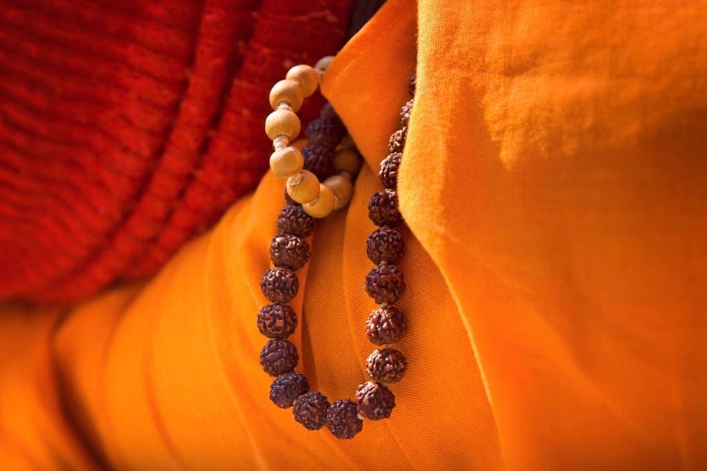 A pandit in saffron robes holding Rudraksha prayer beads